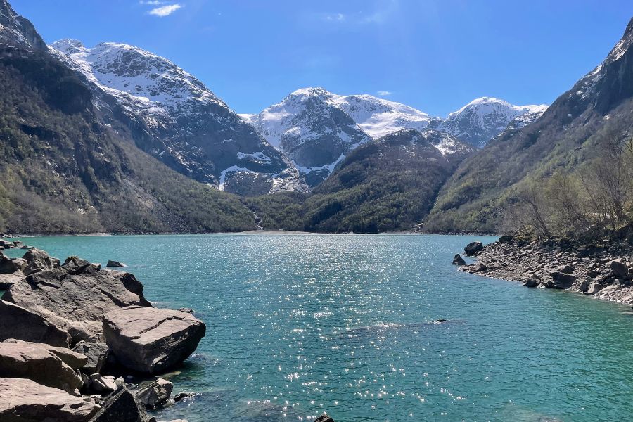 Turquoise Bondhusdalen lake with snowy mountains in the background.