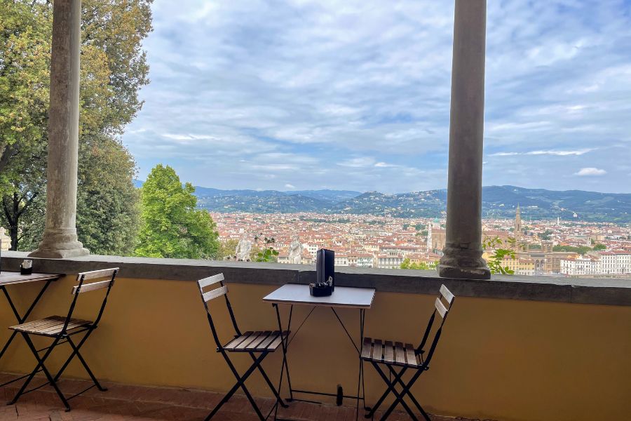 An empty table with two chairs overlooking a scenic view of Florence, Italy.