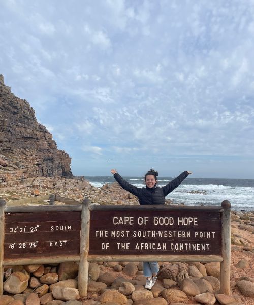 A girl poses with a Cape of Good Hope sign in South Africa.