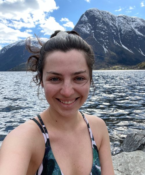 A young woman smiles in a selfie in front of Sandvin lake in Odda, Norway