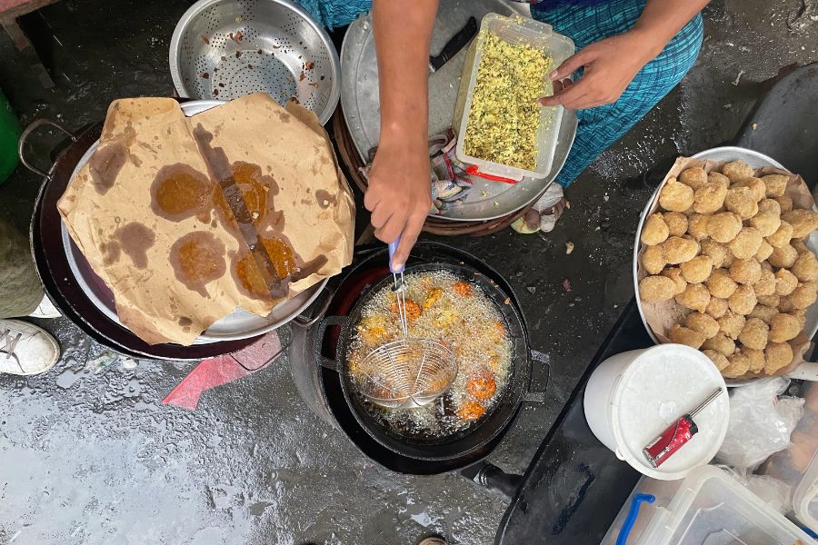 A street vendor in Old Town Mombasa makes fresh falafel by scooping the bean mix into boiling oil