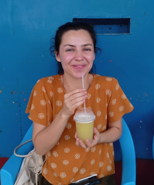 A young white woman smiles with a sugarcane juice, a perfect refreshment during a Mombasa street food tour